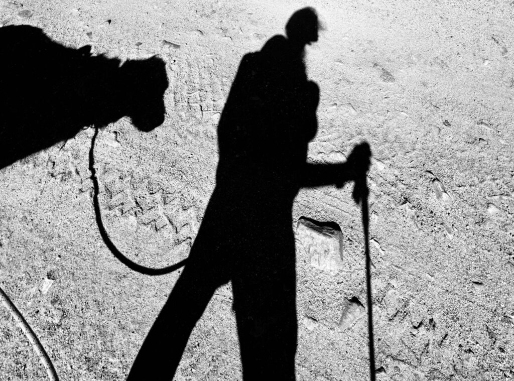 Shadow of person with backpack walking dog